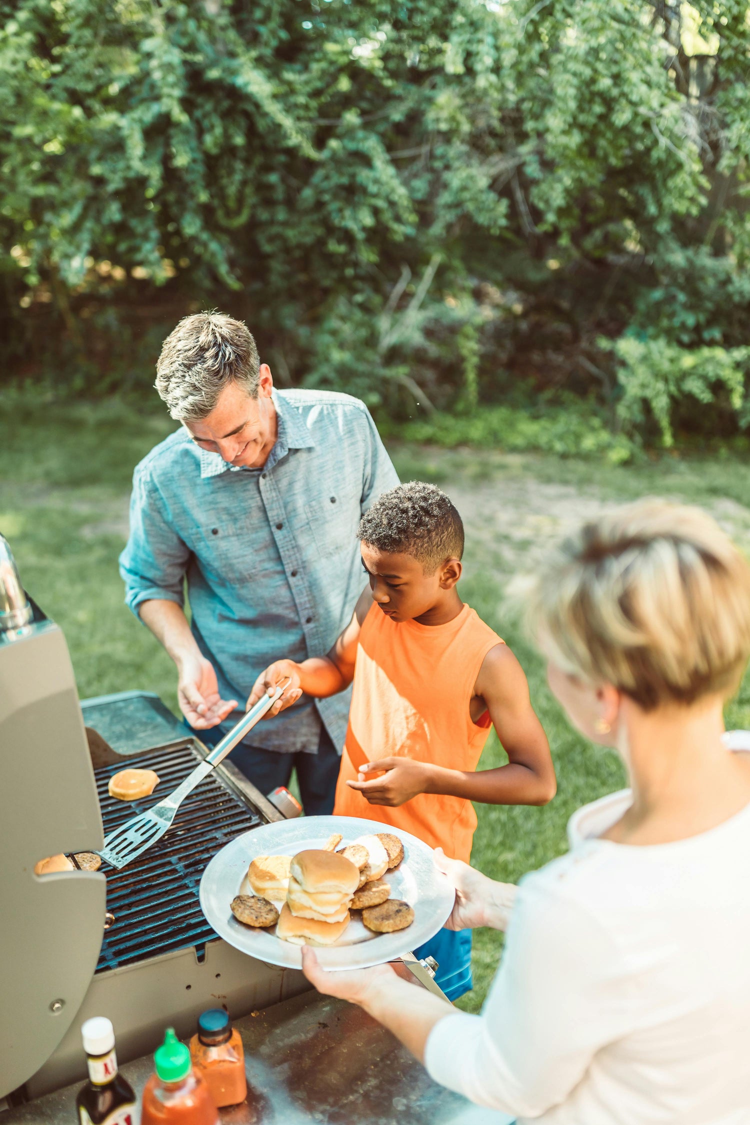 Family grilling outdoors with a plate of food