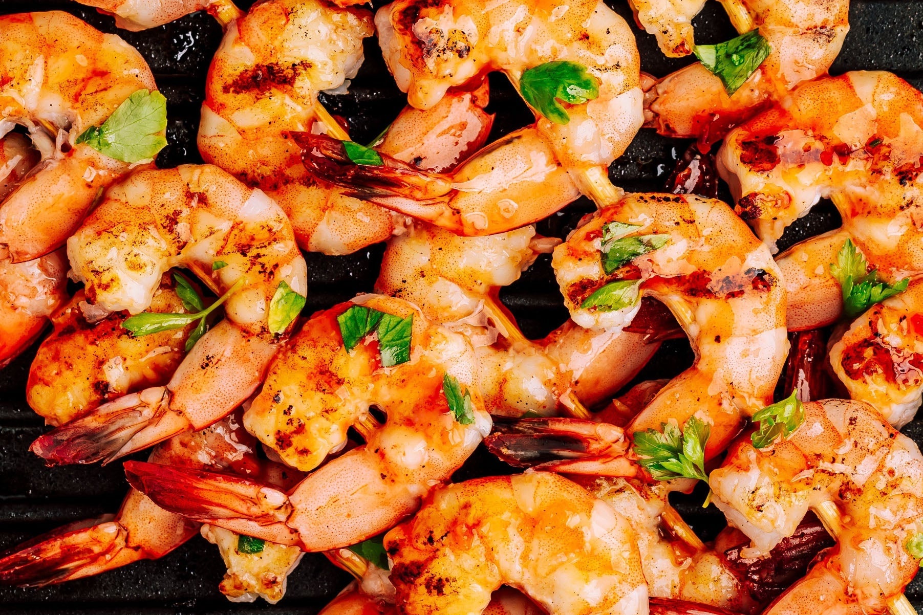 Grilled shrimp with green onions on a black surface